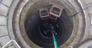 A professional septic technician monitoring a diagnostic control panel during a tank pumping service, showing flow rates and duration factors for a 1500-gallon tank.